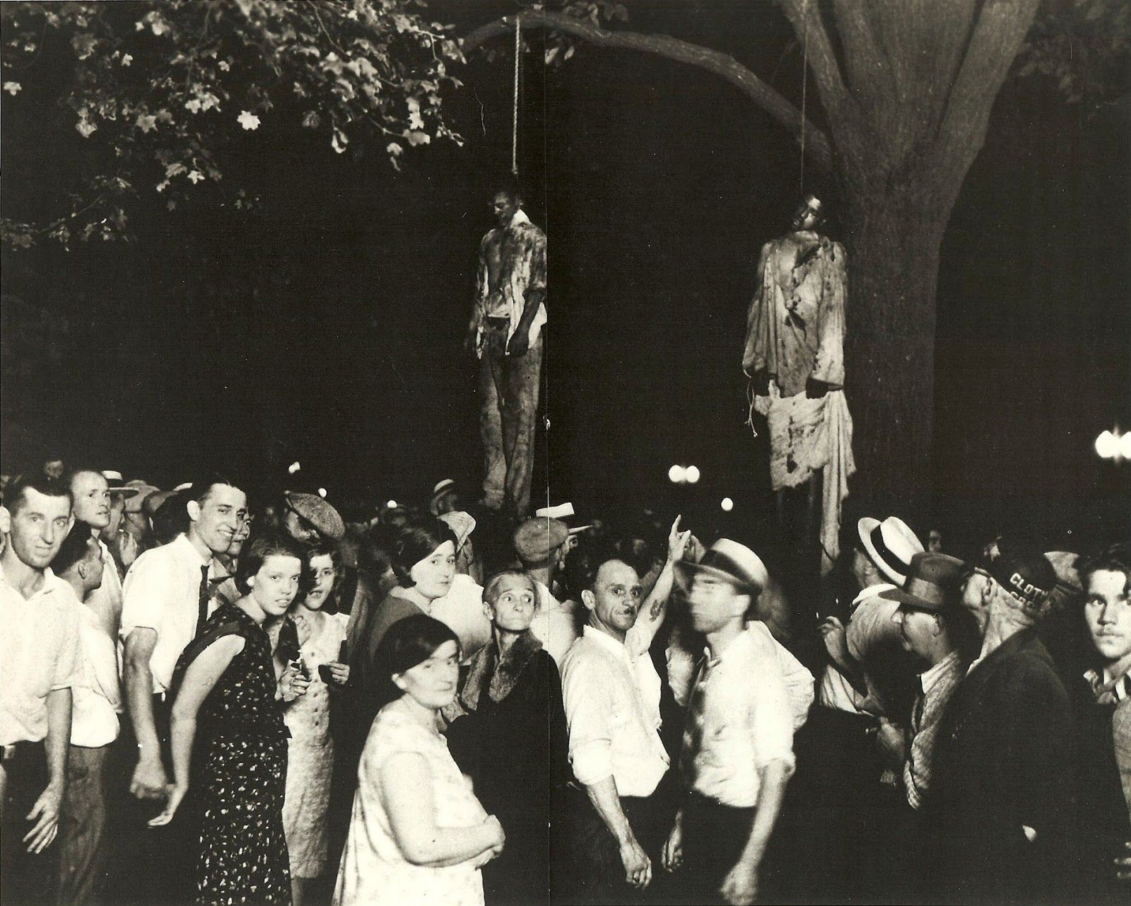 Two black men are hung from trees, surrounded by a white crowd