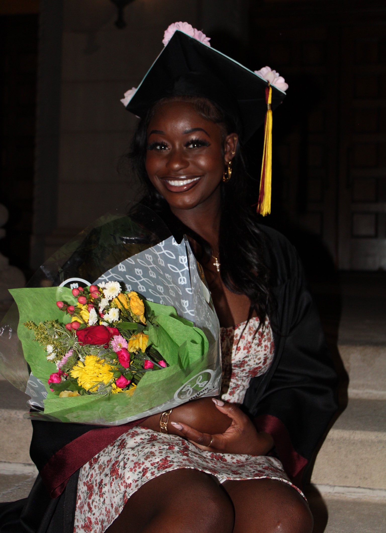 Rachel Okeleye in cap and gown holding a bouquet of flowers.
