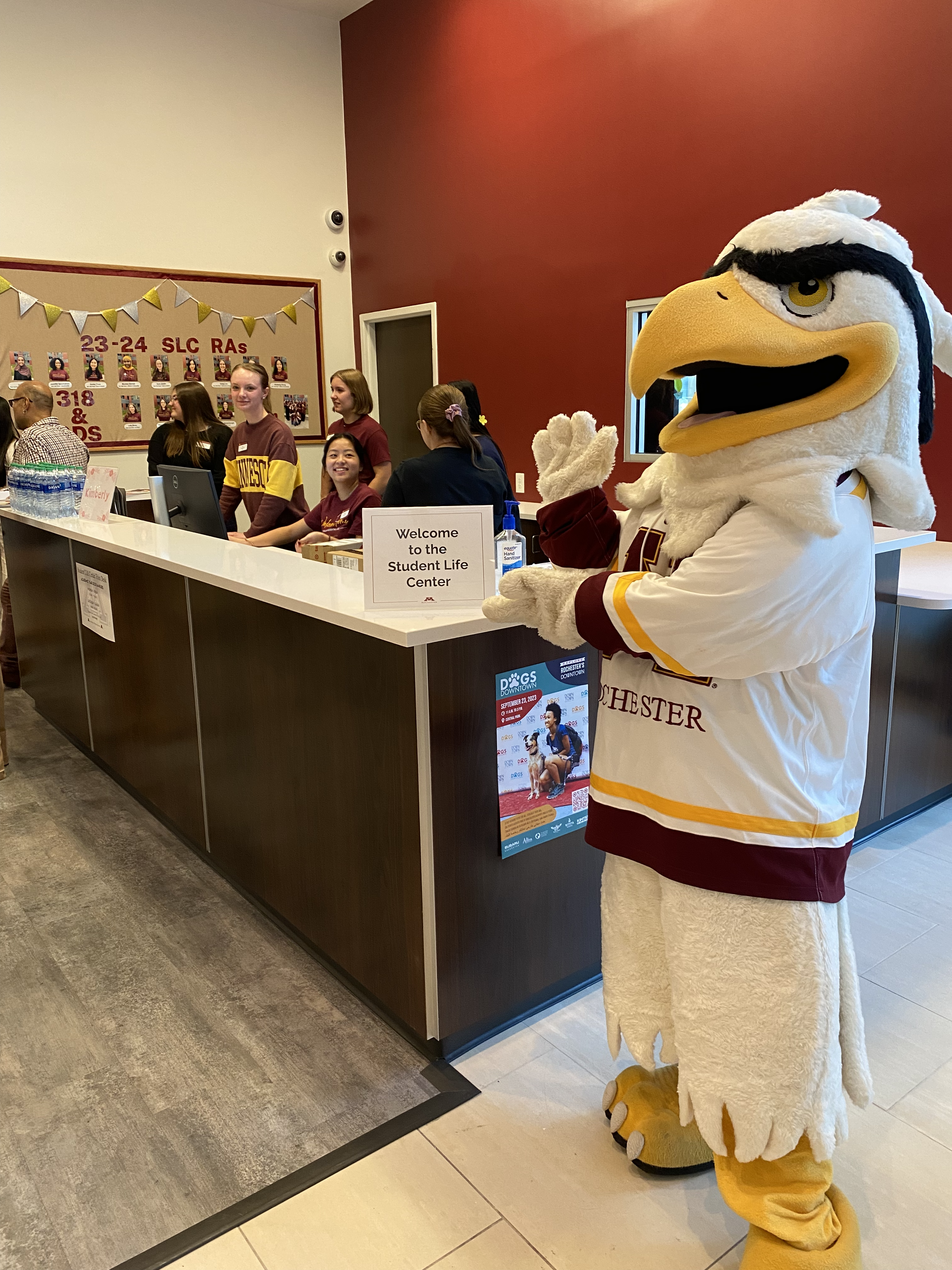 Rockie the Mascot walking standing in front of SLC front desk. 