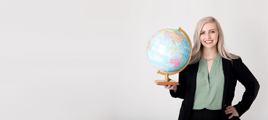 Cassie Kersten, UMR Alumna 2016, holds a globe representing the Public Policy and Global Health career pathway.