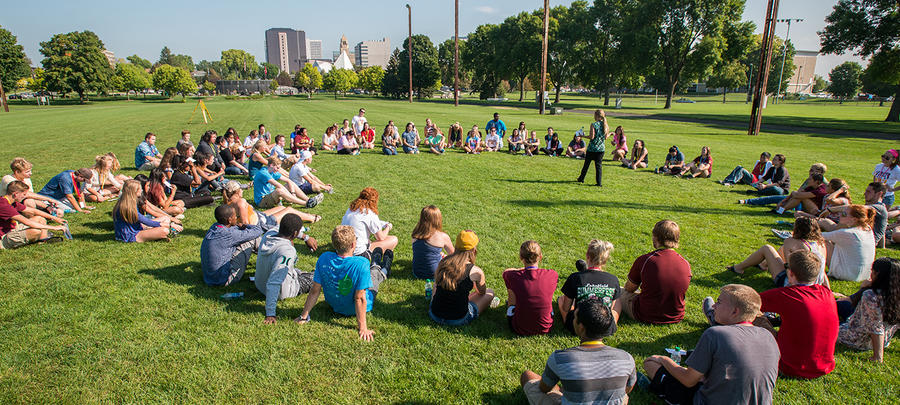 University of Minnesota Rochester students sitting in a grassy field near campus during an orientation event.