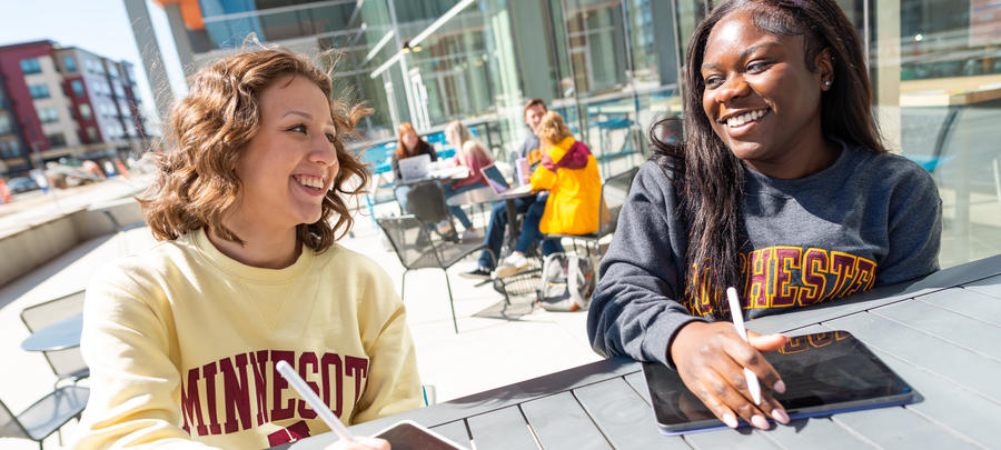 A University of Minnesota Rochester students smiling while working on ipad outside of One Discovery Square.