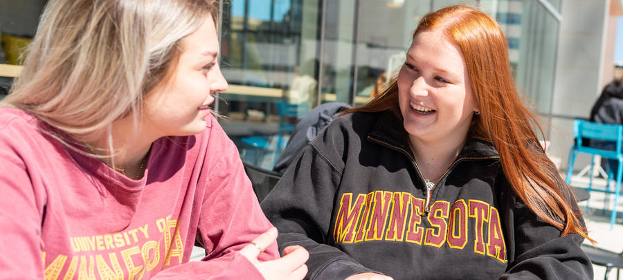 A University of Minnesota Rochester students smiling while working on homework outside of One Discovery Square.