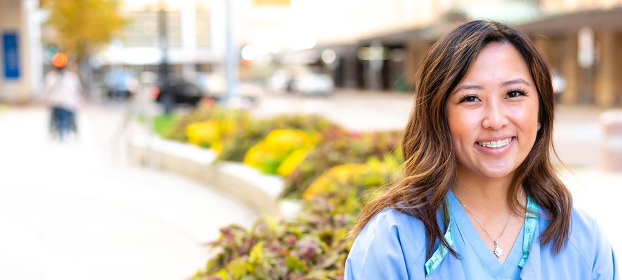 Sarah Vang, UMR Alumna 2021, smiles while sitting outside of Mayo Clinic buildings in Downtown Rochester, Minnesota.