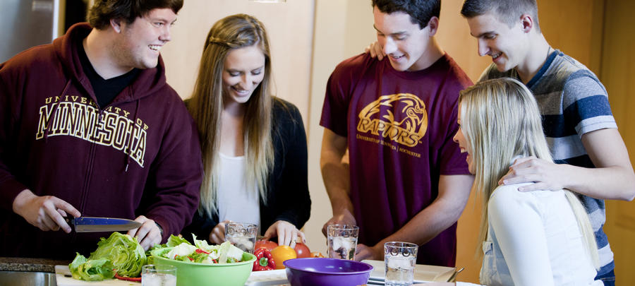 University of Minnesota Rochester students preparing a salad in the kitchen of their 318 Commons apartment